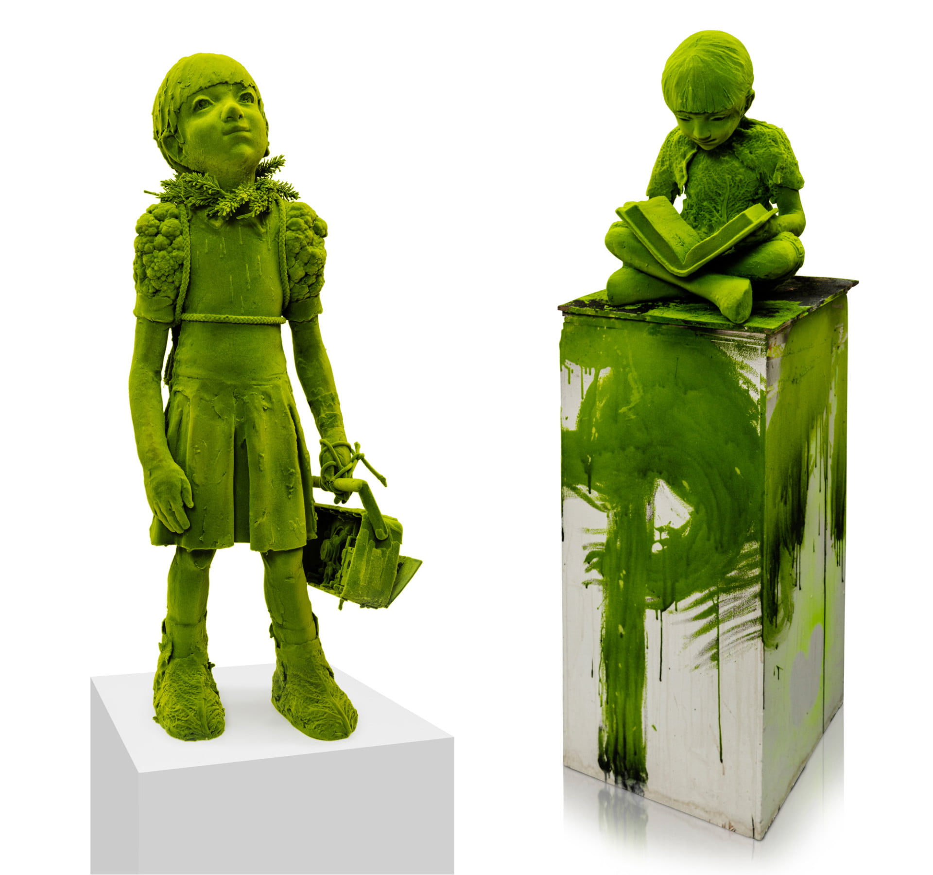 Two sculptures of young figures made from ceramic that are coated in green flocking to make them like they are coated in moss.