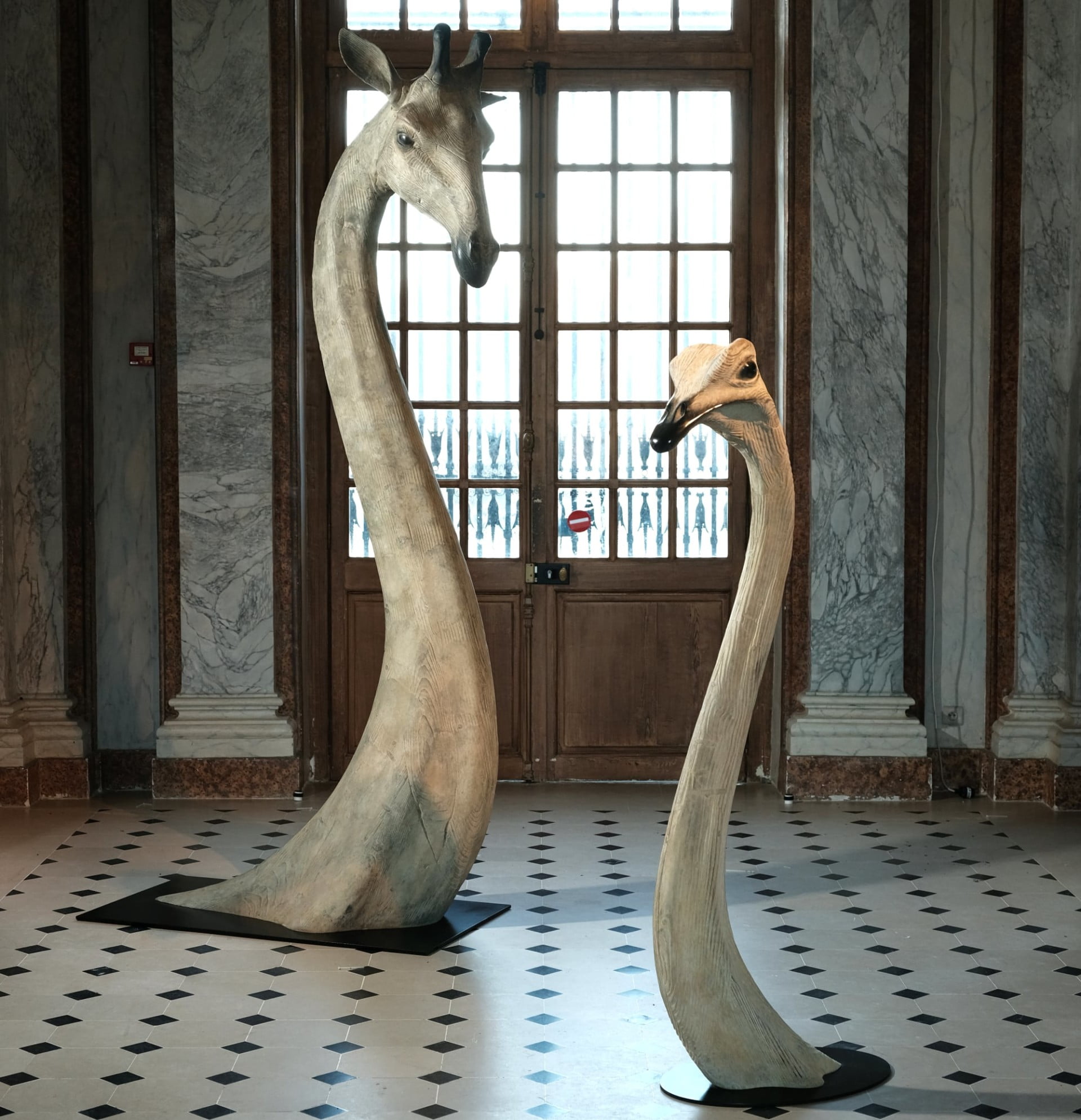 A photo of oversized sculptures of giraffe and emu